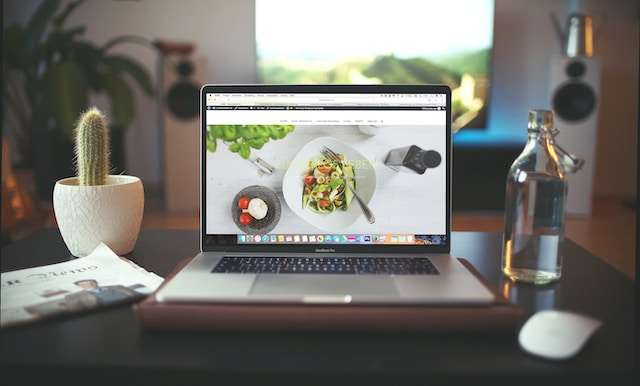 Professional Web Design - Laptop with a food website open with a cactus to the left of the laptop and a bottle of water to the right of it